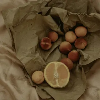 Apricots and a halved grapefruit on brown paper over dusky pink satin
