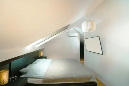 A whitewashed sloping ceiling and a small square window