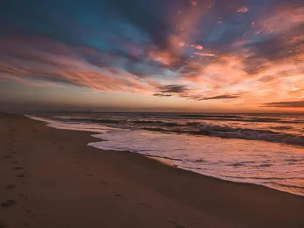 Footprints across wet sand at first light