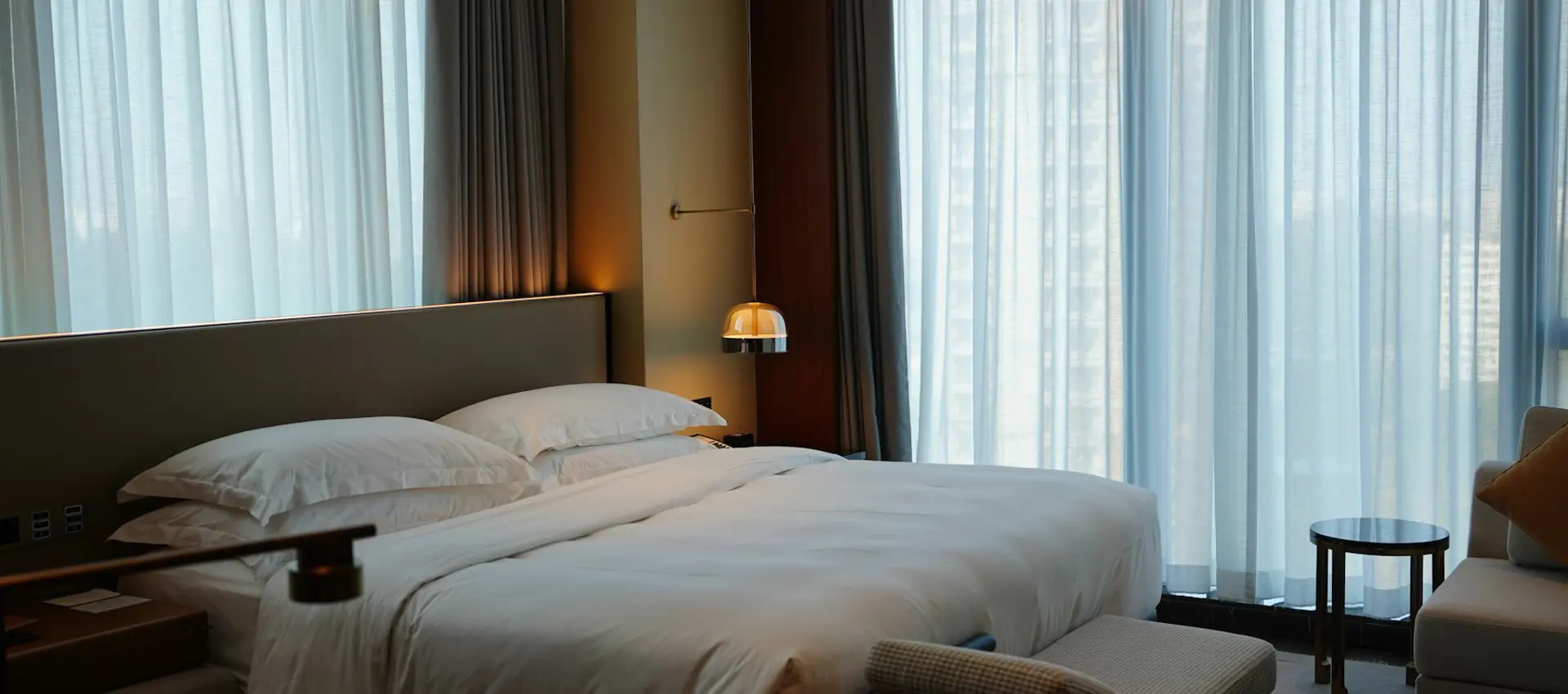 A corner room with a linen-dressed bed and shutters open to the valley