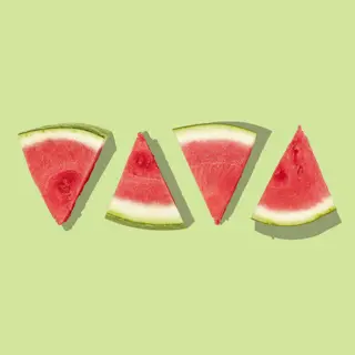 Slices of watermelon laid out on a flat green ground