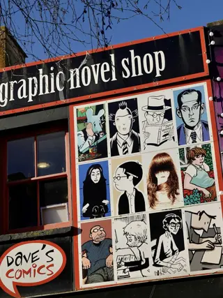 The shopfront under a painted mural, door propped open