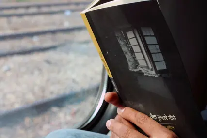 A cushioned window seat with books stacked on the sill