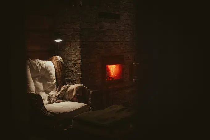 A low-lit sitting room with deep armchairs drawn up to an open fire