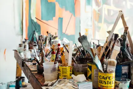 Teenagers painting at a long table in a bright studio