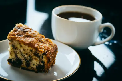 A cup of coffee and a pastry on a stone counter