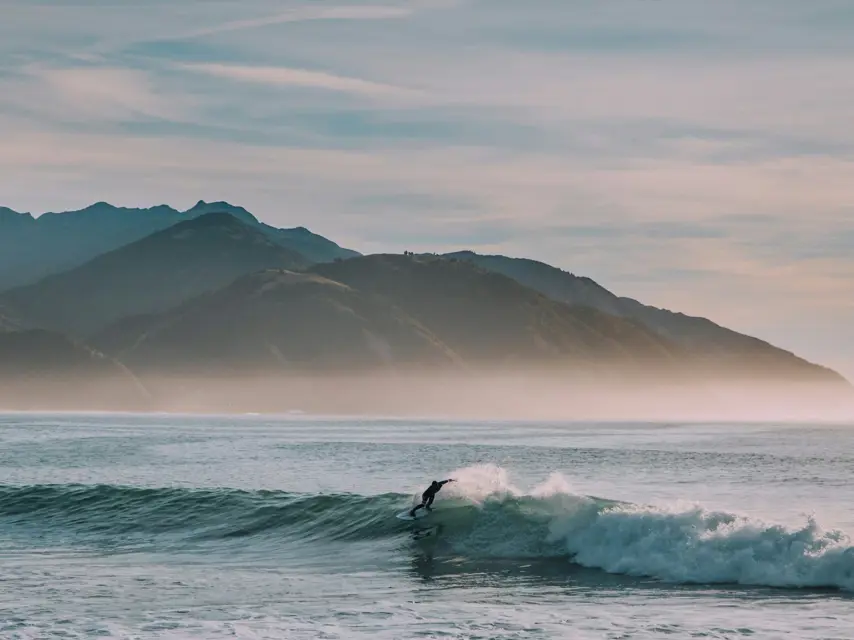 A surfer riding along the face of a green wave