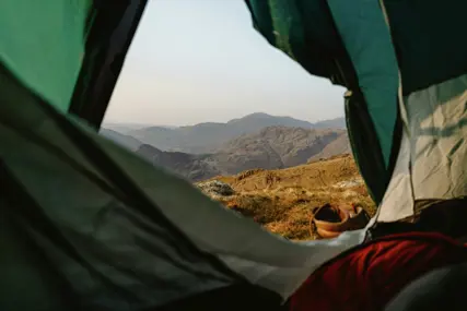 A small tent pitched high with hills behind