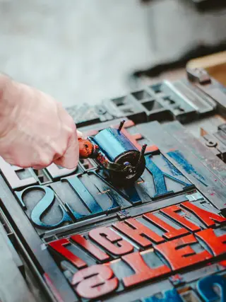 A hand running an ink roller across a plate