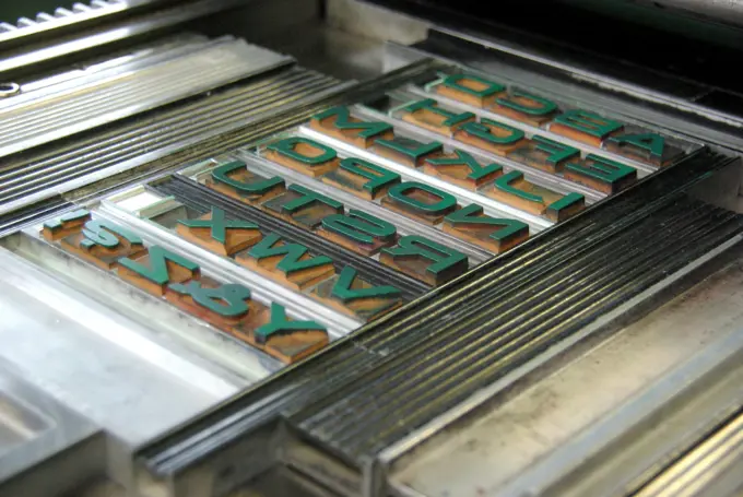 A letterpress with a forme of metal type locked into the bed